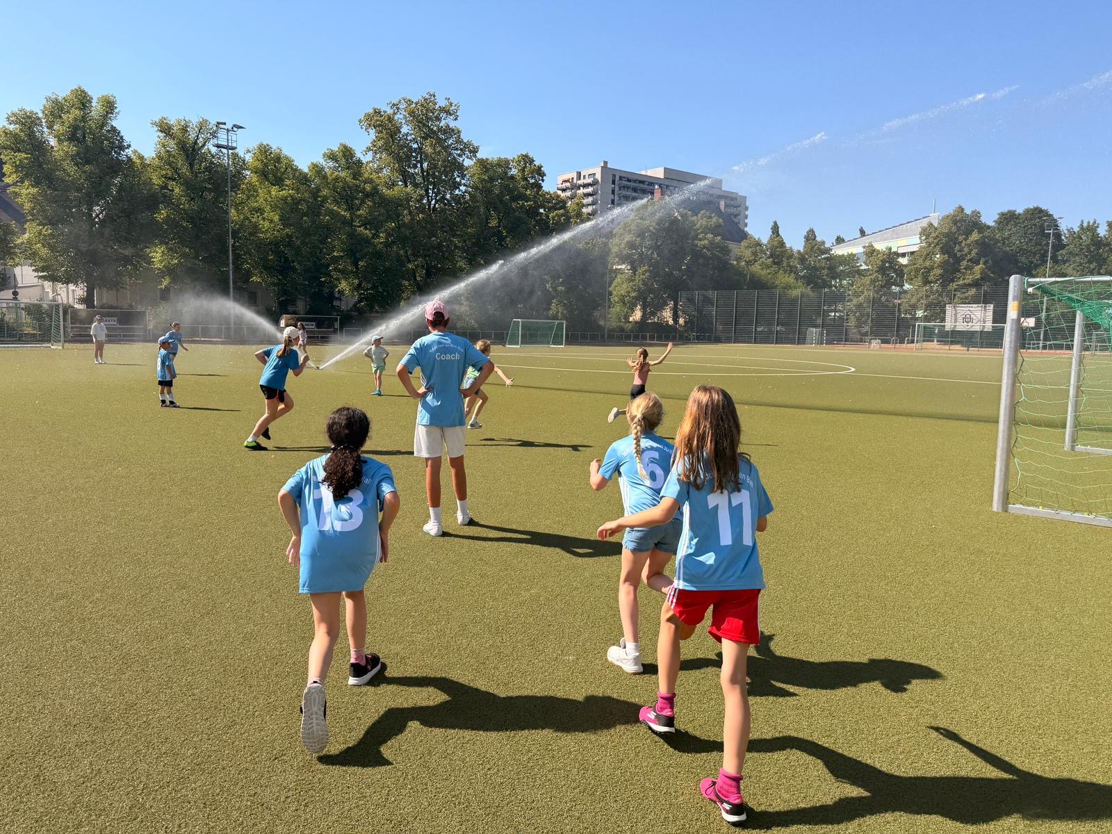 Mädchen auf einem Fußballplatz mit Rasensprenger